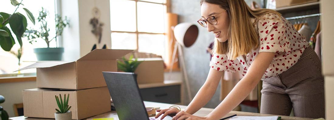 Young female entrepreneur receiving new orders in her internet retail clothing shop. Find internet retail store insurance.