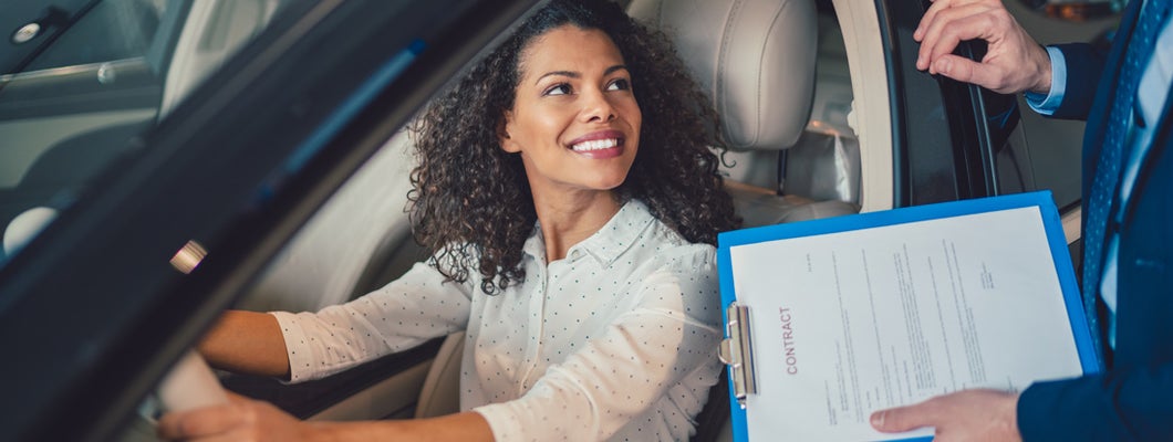 Woman in the showroom test driving a new car. 8 tips for buying your first car.