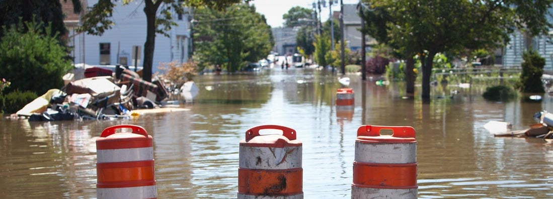 Orange blockade cones on a flooded street. Find Washington flood insurance.