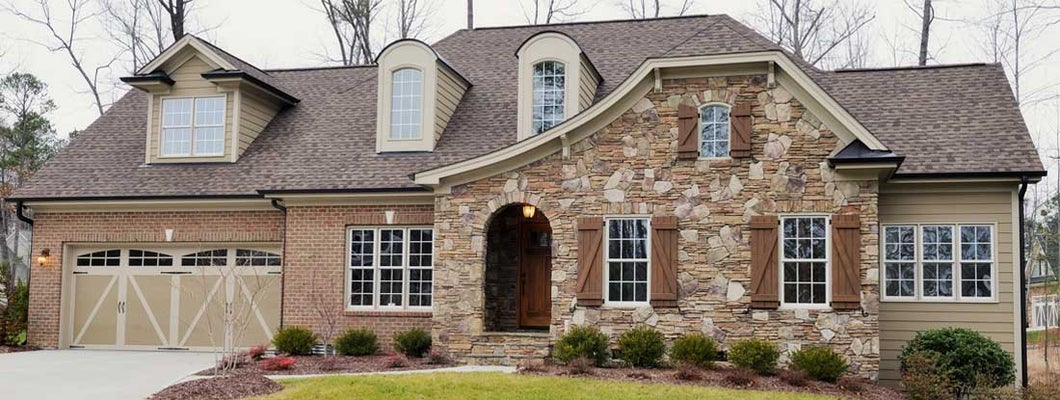 Home exterior with landscaped front yard with grass and bushes in foreground. Find Wilmington NC homeowners insurance.