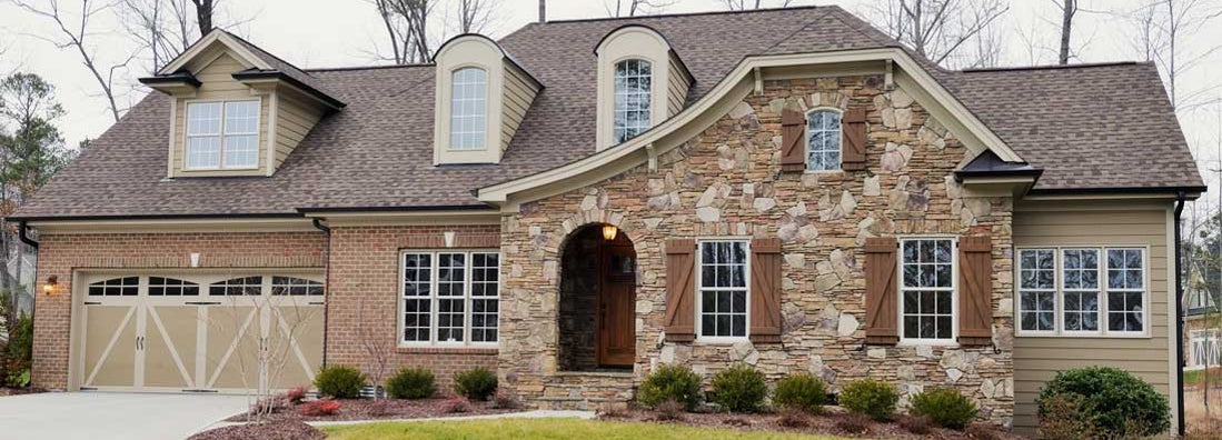 Home exterior with landscaped front yard with grass and bushes in foreground. Find Wilmington NC homeowners insurance.