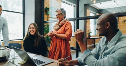 Businesspeople smiling cheerfully during an office meeting. Employee Benefits: A Complete Guide.