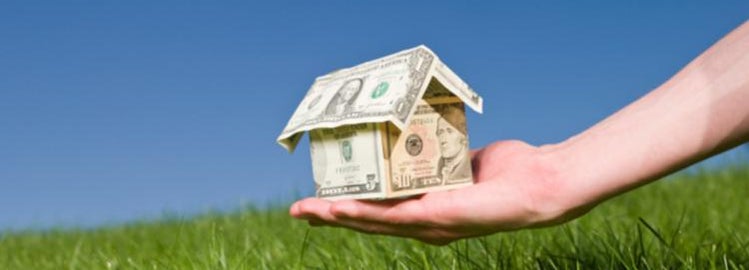 Hand holding money in the shape of a house