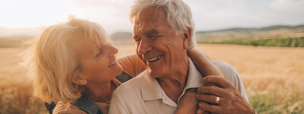 Mature couple looking away in park. Find funeral and burial insurance.