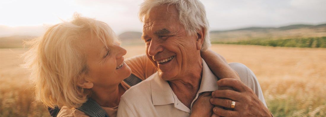 Mature couple looking away in park. Find funeral and burial insurance.