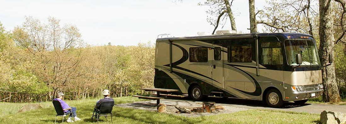 Couple relaxing near RV in Mississippi. Find Mississippi RV Insurance.