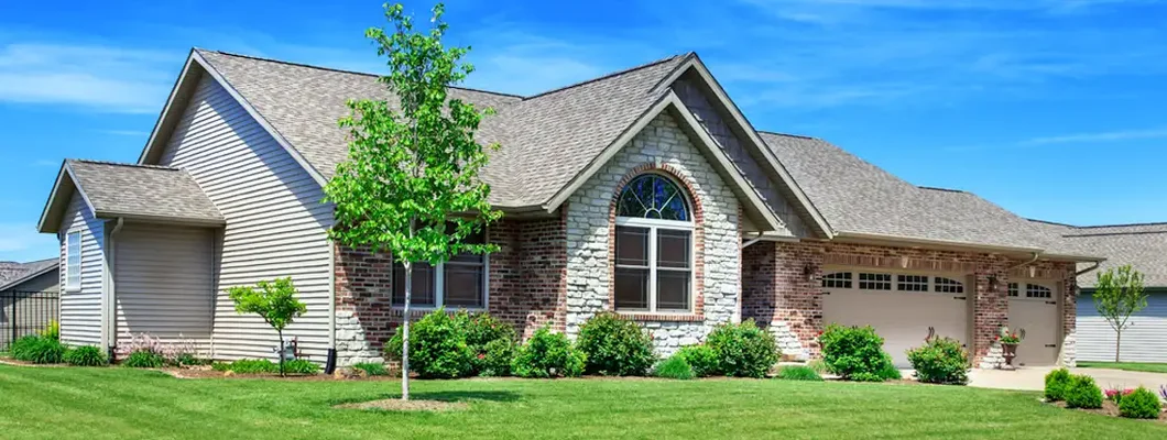 One story home with a landscaped yard and blue sky in the background. Find Lansing, Michigan homeowners insurance.