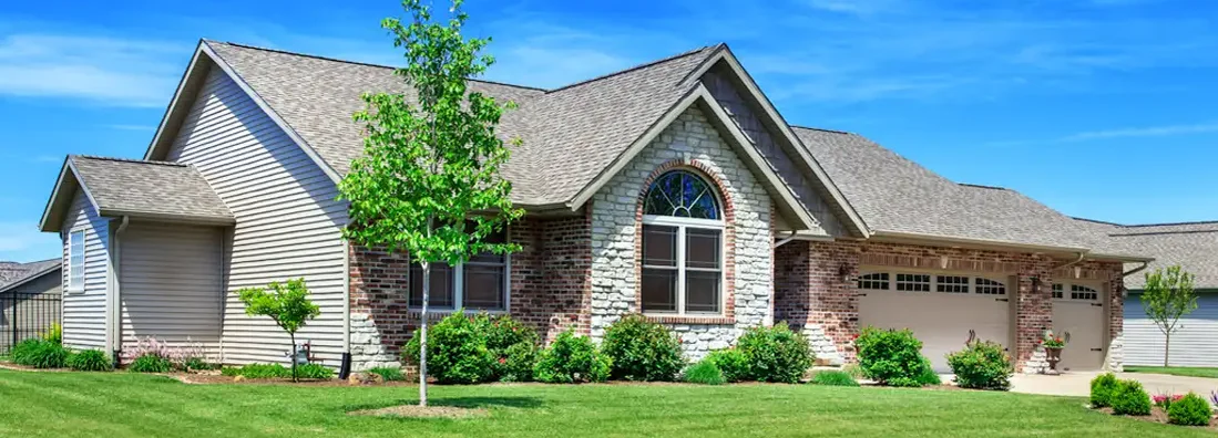 One story home with a landscaped yard and blue sky in the background. Find Lansing, Michigan homeowners insurance.