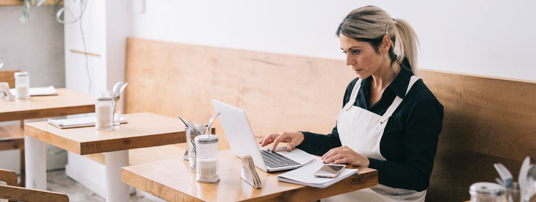 Cafe Manager working with laptop. What small business owners should know about cybersecurity risks.