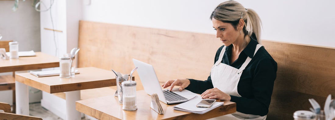 Cafe Manager working with laptop. What small business owners should know about cybersecurity risks.