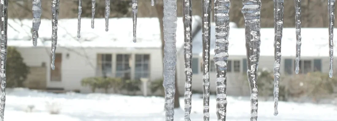 Icicles hang from the eaves on a cold winter morning. Ice Dams in Illinois: Insurance Coverage and Top Prevention Tips.