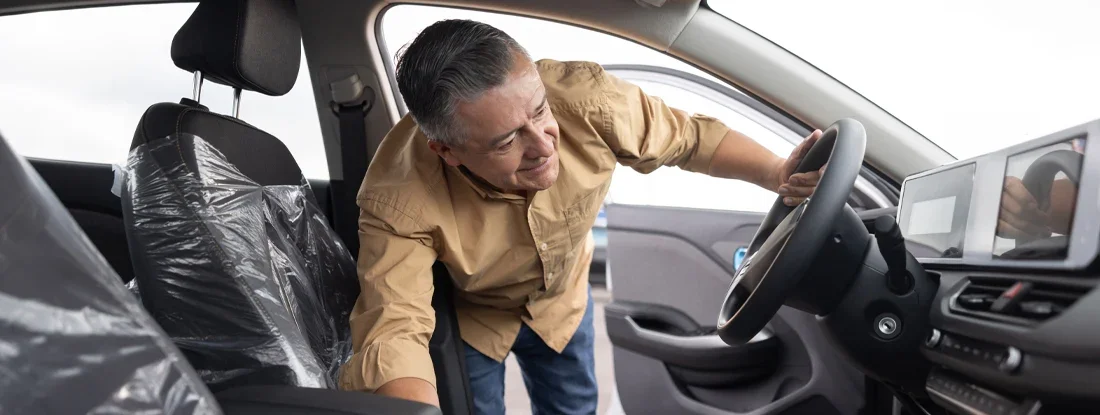Man looking at the interior of a car while shopping at the dealership. The Definitive 5 Step Car Buying Guide.