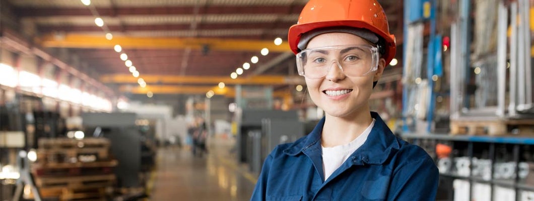 Woman with orange helmet in factory warehouse. Workers Compensation for Businesses.