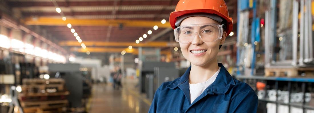 Woman with orange helmet in factory warehouse. Workers Compensation for Businesses.