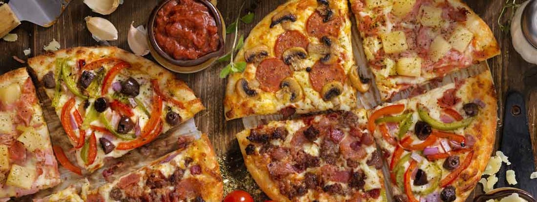 Pepperoni and Mushroom, Ham and Pineapple, All Meat or Vegetarian Pizzas on a wood background . Find Pizza Parlor Insurance.