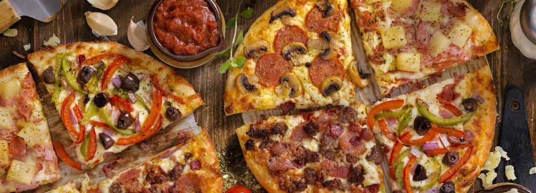 Pepperoni and Mushroom, Ham and Pineapple, All Meat or Vegetarian Pizzas on a wood background . Find Pizza Parlor Insurance.