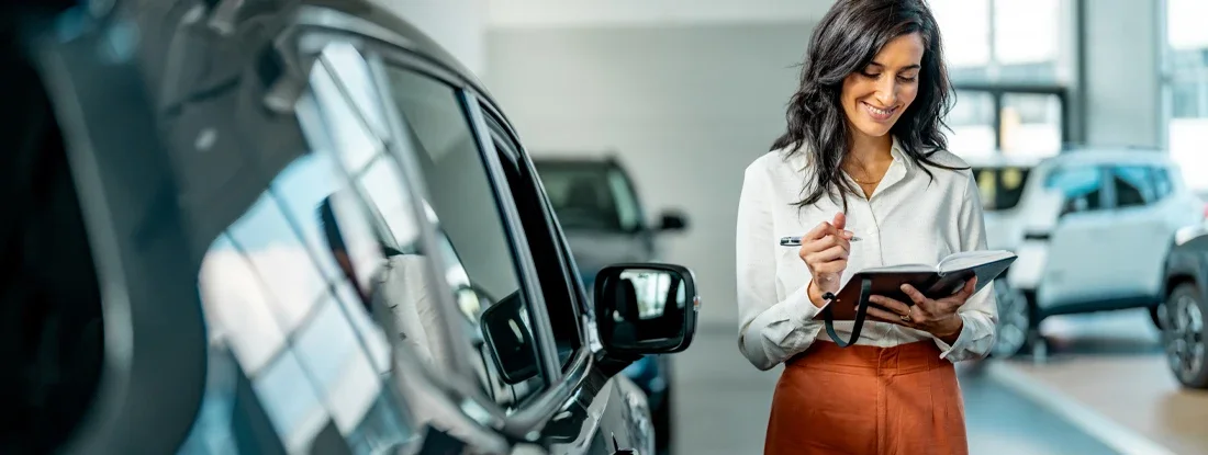 Smiling saleswoman working at a car dealership. What Is an Auto Broker?