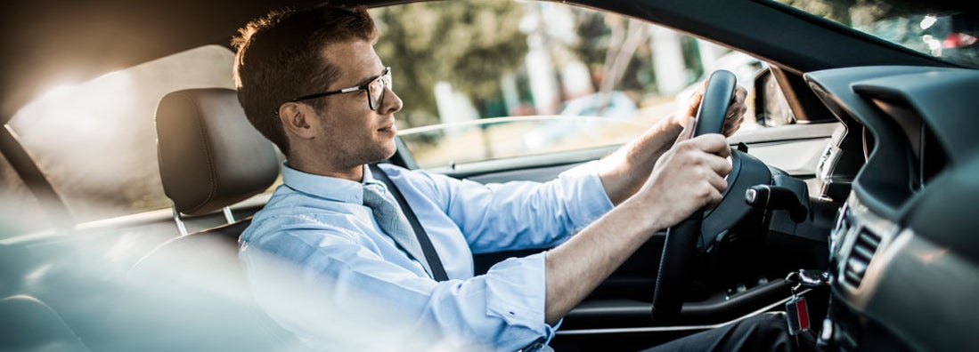 Close up photo of a businessman driving a car in city. Find Mobile Alabama car insurance.