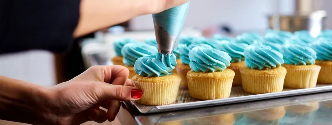 Woman in bakery icing cupcakes. Find business liability insurance.