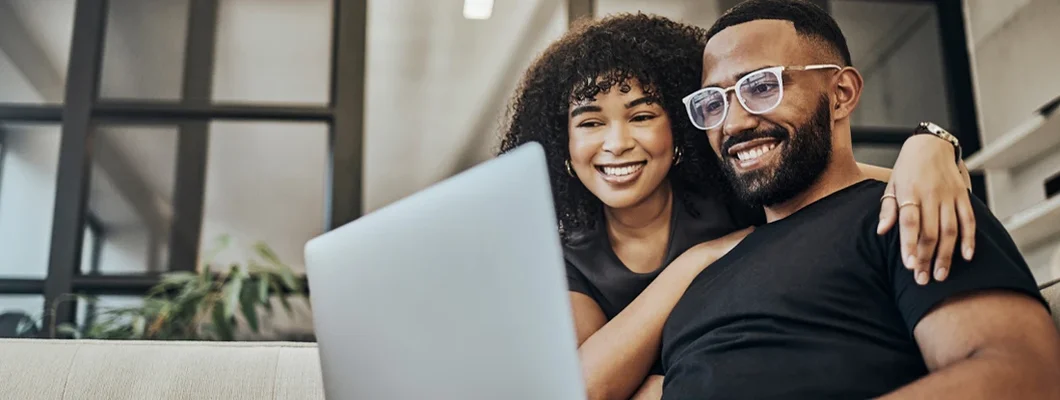 Couple on sofa researching insurance on laptop in living room. Find personal liability insurance for renters.