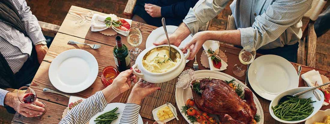 mashed potatoes being passed during a thanksgiving feast at a dining table