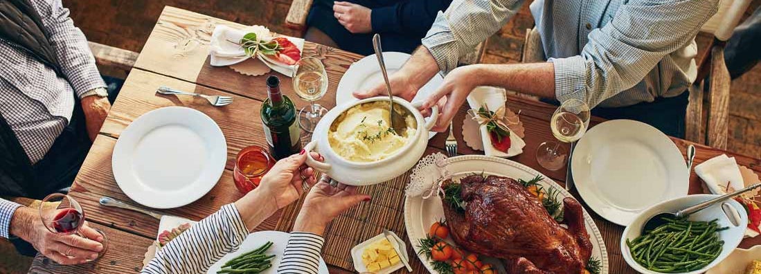 mashed potatoes being passed during a thanksgiving feast at a dining table