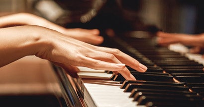 Close up view of female hands playing piano. Find Body Part Insurance.