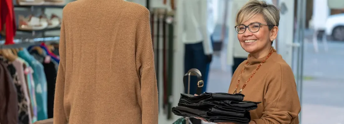 Woman store clerk working in boutique clothing shop. Find Irvine, California business insurance.