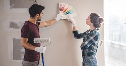 Young couple choosing the right color for their wall in new home. 6 diy home renovation projects that impact your insurance.