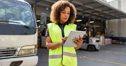 Woman supervising the dispatch of trucks at a distribution warehouse. Commercial Vehicle Coverage Types.