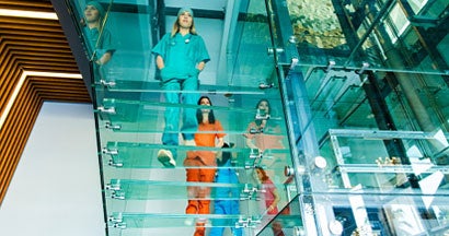 Medical professionals walking on modern glass staircases. Find professional liability insurance.