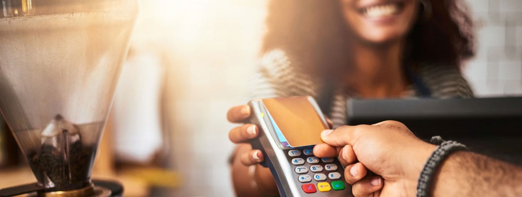 Closeup shot of a customer making a credit card payment in a cafe. Tips to boost POS security for small business owners. 