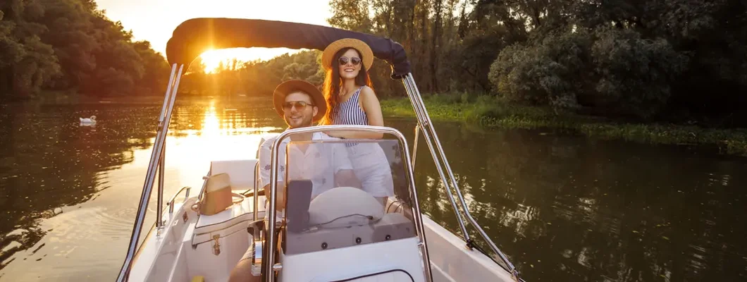 Couple relaxing on the river riding a boat in sunset. Find Arkansas Boat Insurance.