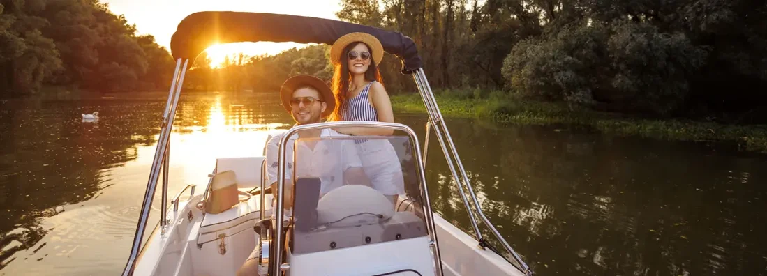 Couple relaxing on the river riding a boat in sunset. Find Arkansas Boat Insurance.