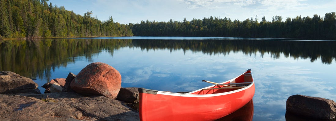 A red canoe rests on a rocky shore in the Boundary Waters of Minnesota