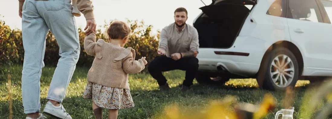 Young Family Enjoying Road Trip with SUV in background. Find SUV Insurance.