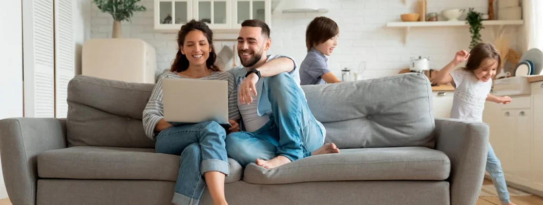 Active kids running around as parents rest on sofa using laptop. How to Find the Best Homeowners Insurance in Herndon, Virginia.