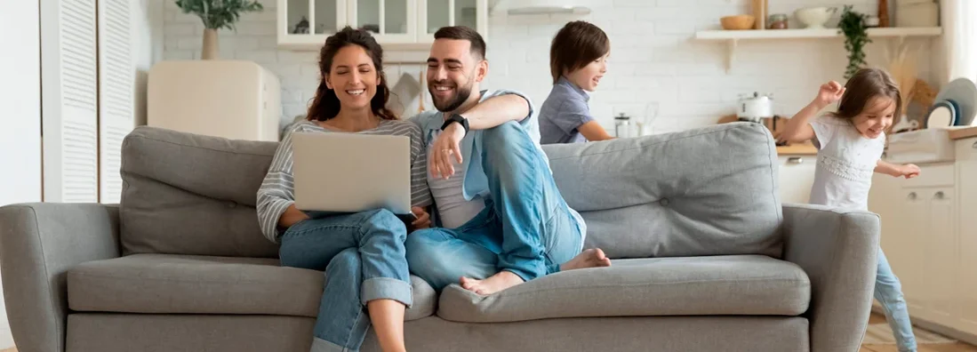 Active kids running around as parents rest on sofa using laptop. How to Find the Best Homeowners Insurance in Herndon, Virginia.