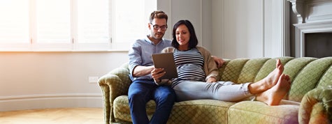 Shot of a pregnant woman and her husband sitting on their sofa using a digital tablet