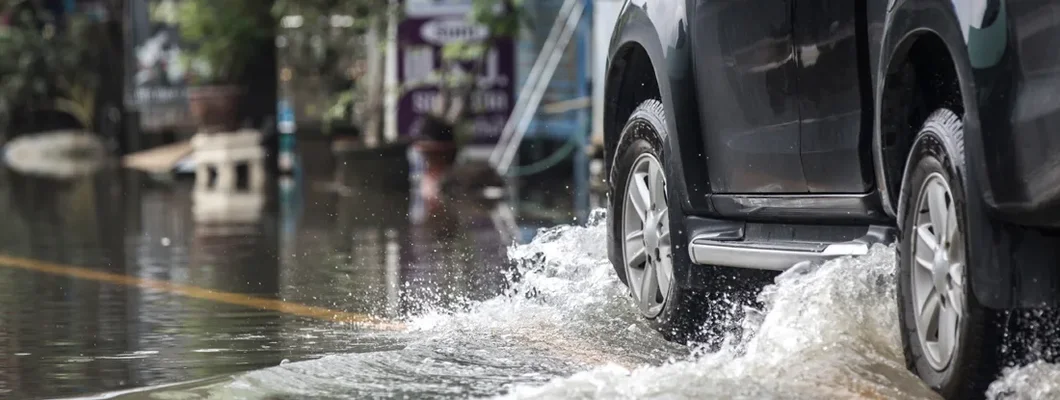 Black pickup truck driven through a flooded road. Does Car Insurance Cover Flood Damage?