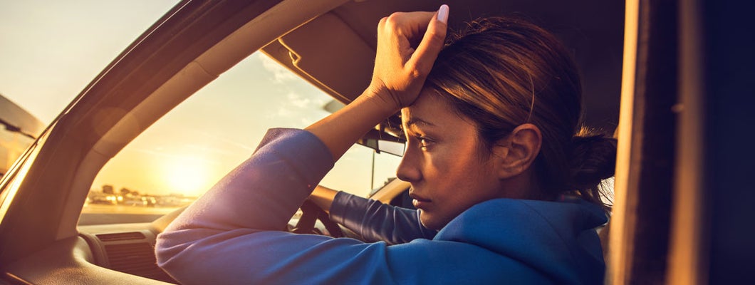 Sad woman having problems while driving a car at sunset. This is why your car insurance is making you broke.