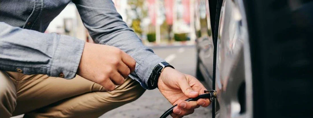 Teen crouching on the gas station and inflating tire. Teens and Tire Safety: What Driver's Ed Doesn't Teach Them.