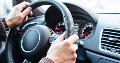 Man driving modern car, holding steering wheel in city traffic. Top 20 Defensive Driving Tips to Keep You Safe. 