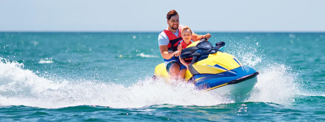 Father and son having fun on jet ski at summer vacation. Find PWC Liability Insurance.