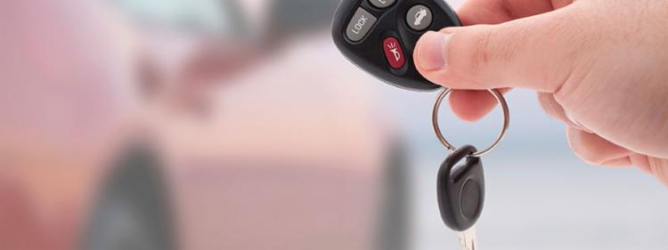 Holding keys up in front of a car.