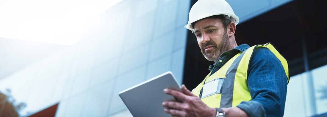 Engineer consultant using a digital tablet on a construction site. 1099 Employee Taxes and Workers' Compensation.