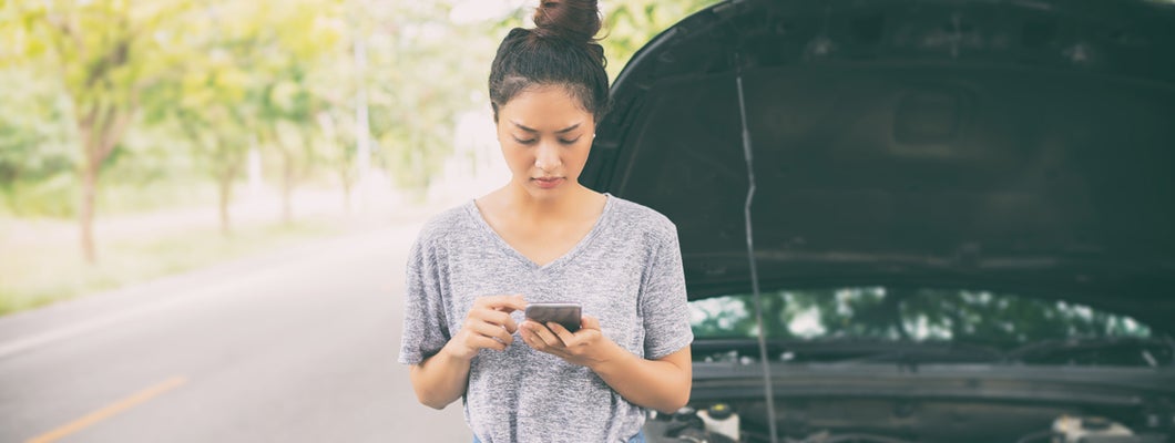 Woman using mobile phone after a car breakdown on street