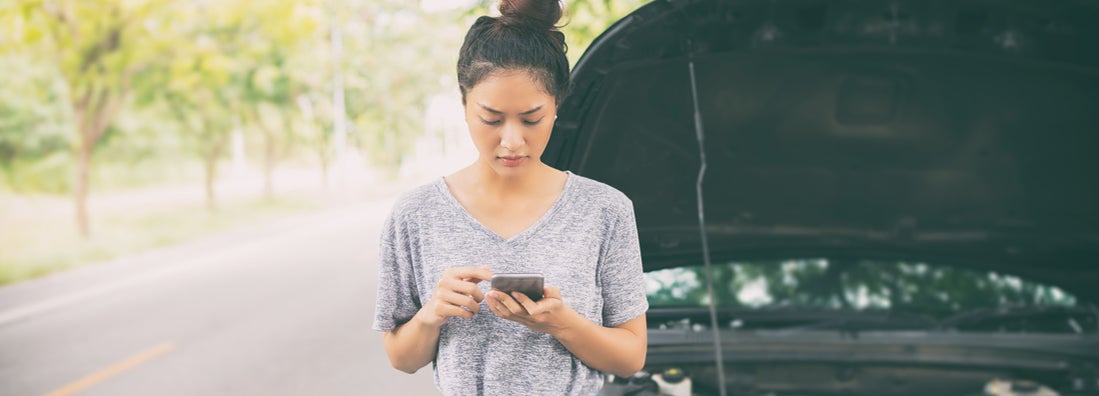 Woman using mobile phone after a car breakdown on street