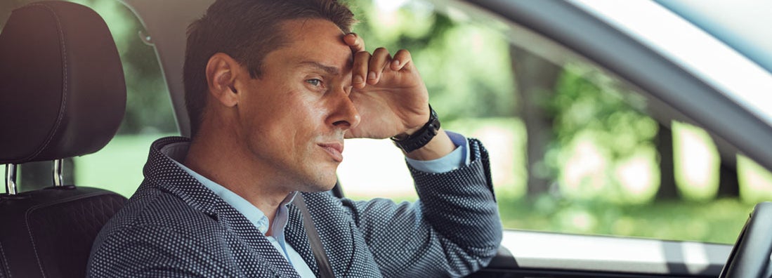 Frustrated businessman in a suit driving his car.  Simple signs you have the worlds worst insurance.