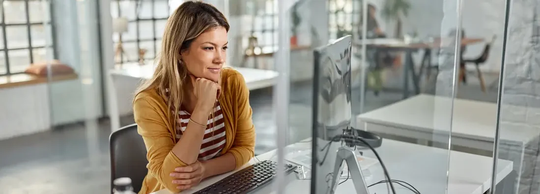 Smiling female programmer working on computer in the office.  Find Papillion, Nebraska business insurance.